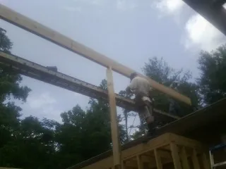 Carpenter setting a ridge beam over a new addition frame — Ice Dam Removal by Roofing Brothers in Baltimore