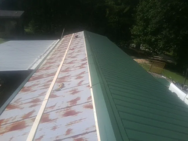 Old rusted panels beside newly installed green metal roofing — Wind Damage Roof Repair by Roofing Brothers in Baltimore