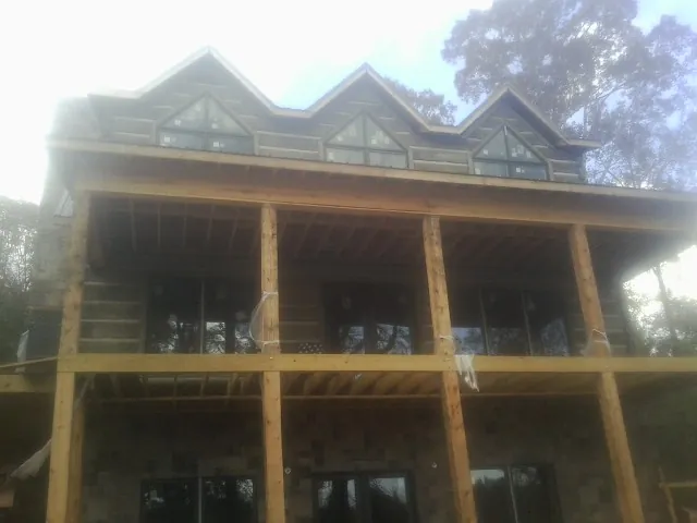 Dormers and porch framing on a large log home under construction — Roof Coating work by our crew in Baltimore