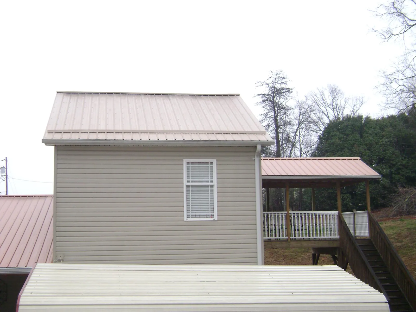 Tan metal roofs on a two story addition and attached porch, from a Roof Replacement job in Baltimore